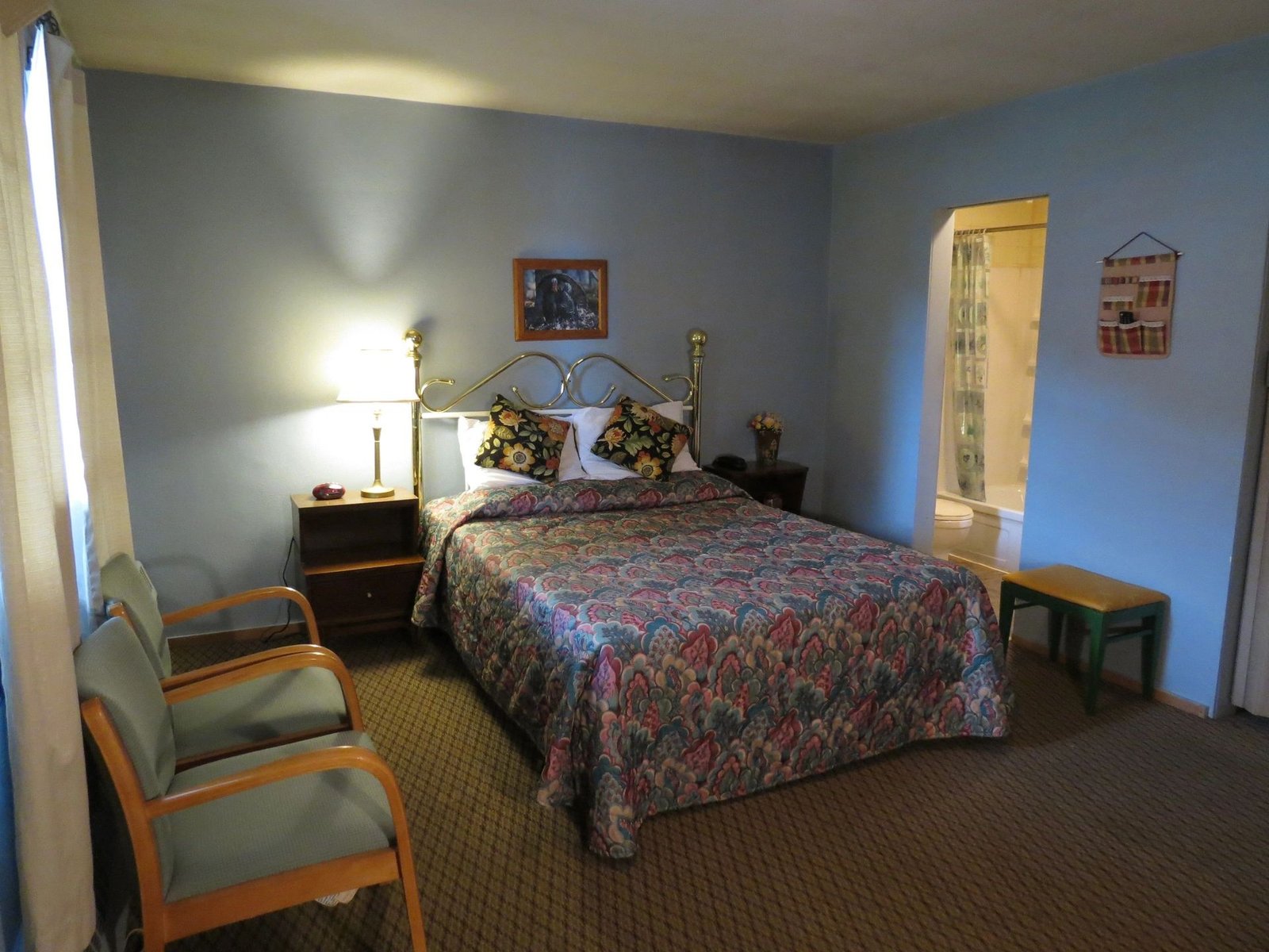 Standard Room with a full bed, lamp and reading chair